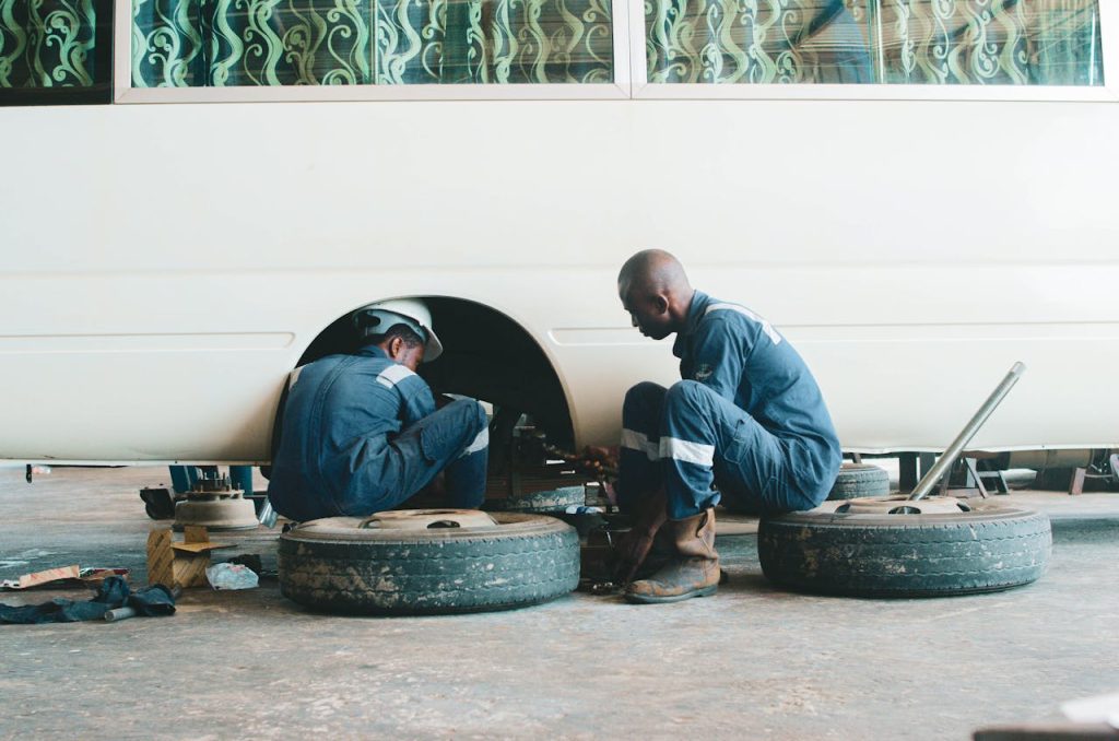 pexels photo 12555009 Two auto mechanics working on repairing a vehicle's wheel in a garage setting.