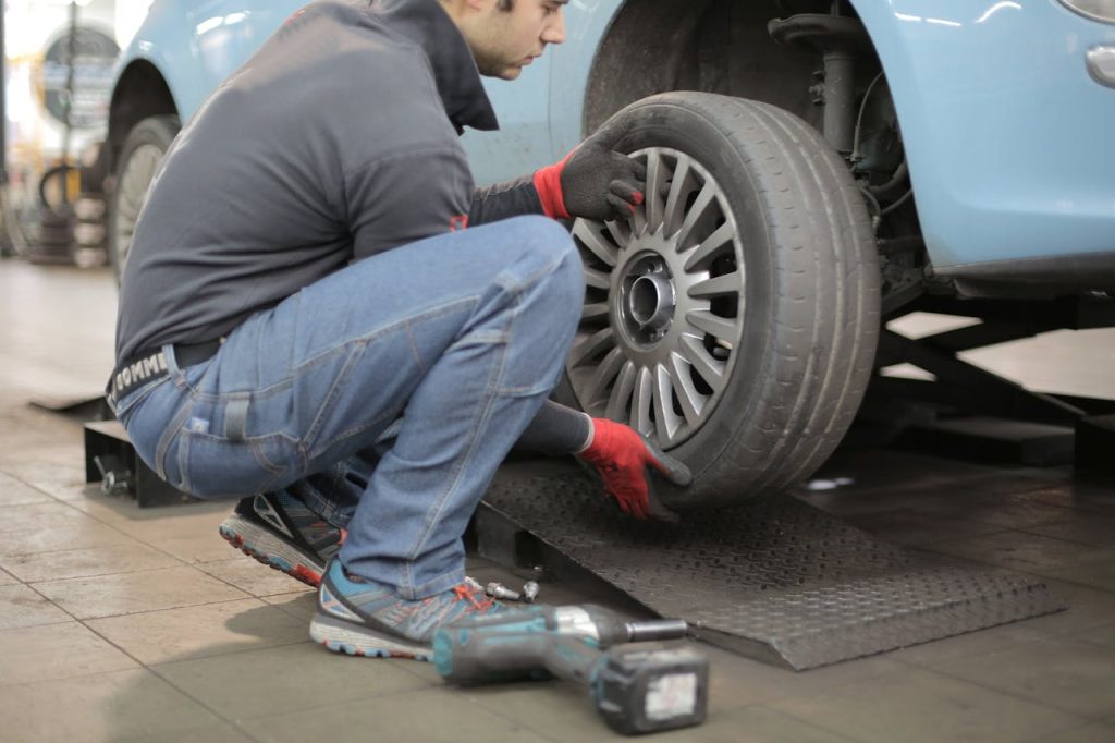 pexels photo 3806249 Mechanic changing a car tire indoors, using tools for vehicle maintenance.