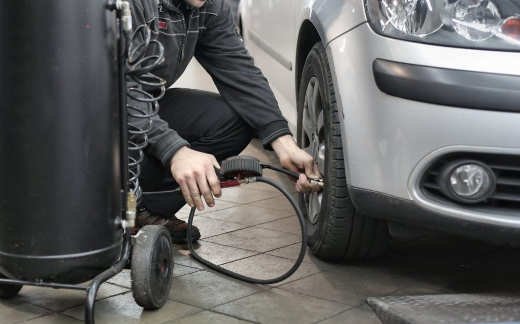 pexels photo 3807386 Mechanic inspecting and adjusting tire pressure in an auto repair shop.