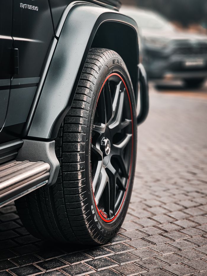 Detailed view of a luxury SUV wheel with stylish design and red accents. Modern and powerful.