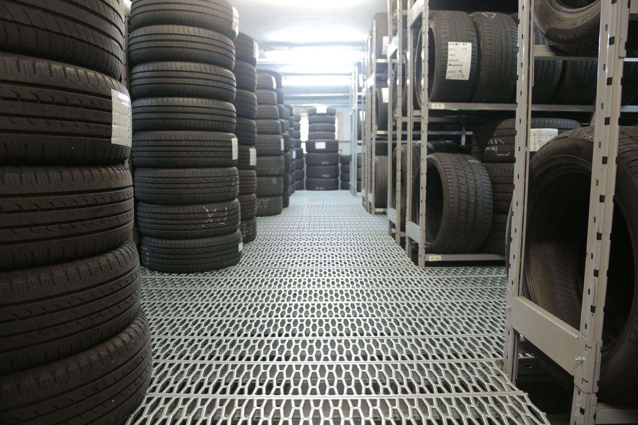 Rows of stacked tires in an indoor industrial warehouse for storage.